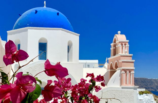 Blauw-witte koepelkerk in Oia met bougainvillea